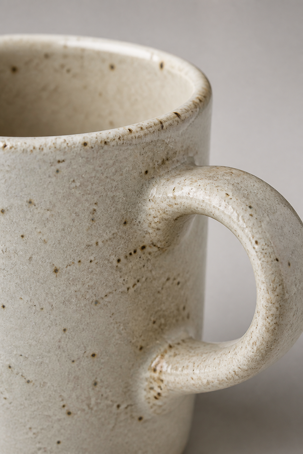 Close-up of the mug rim, matte stoneware speckling, and handle connection